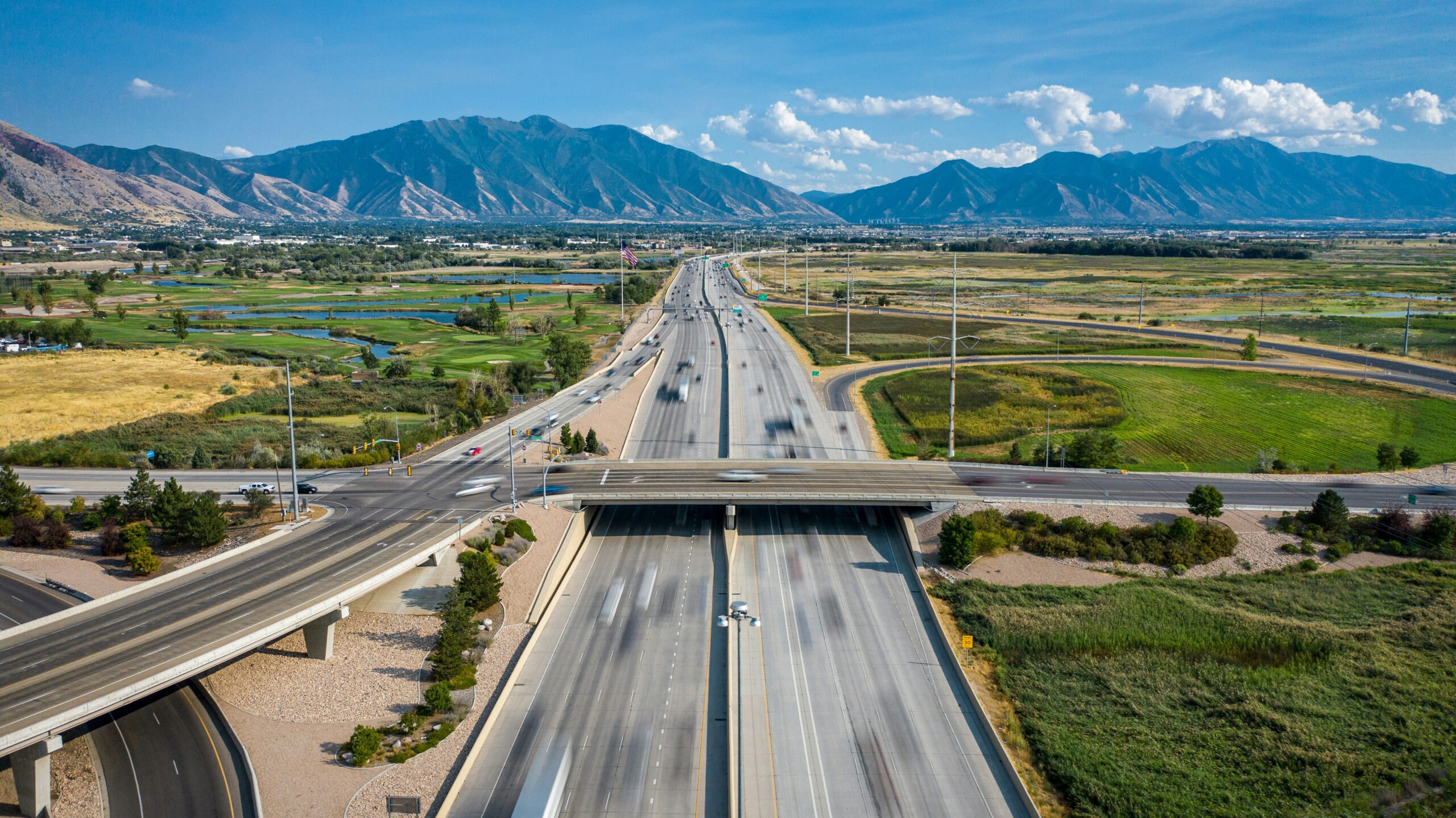 Cars drive on a freeway with mountains in the distance.